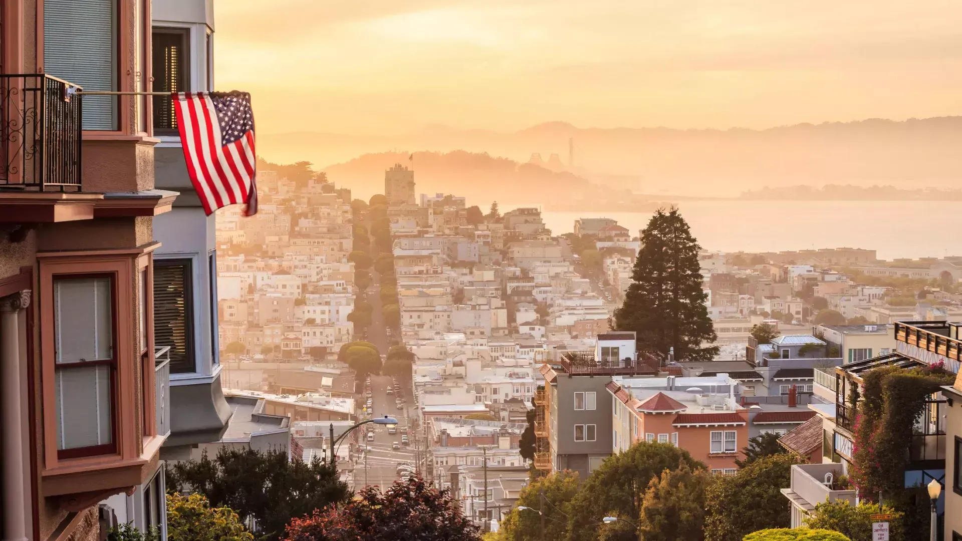 Une vue de San Francisco depuis le sommet d'une colline, avec un drapeau américain flottant au premier plan.