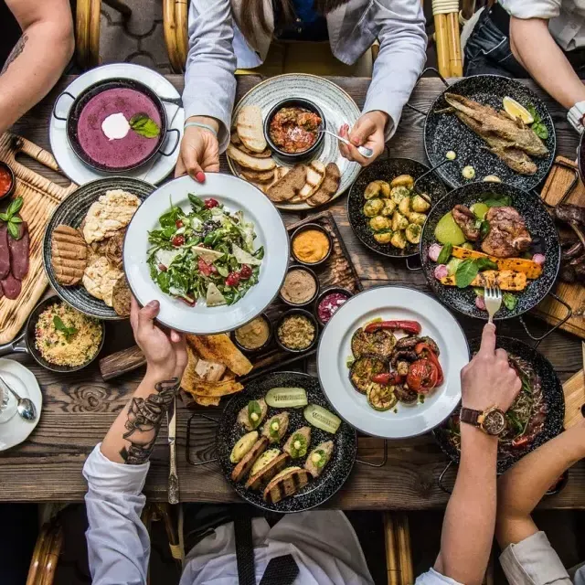 Des gens assis à une table à manger, partageant de la nourriture.