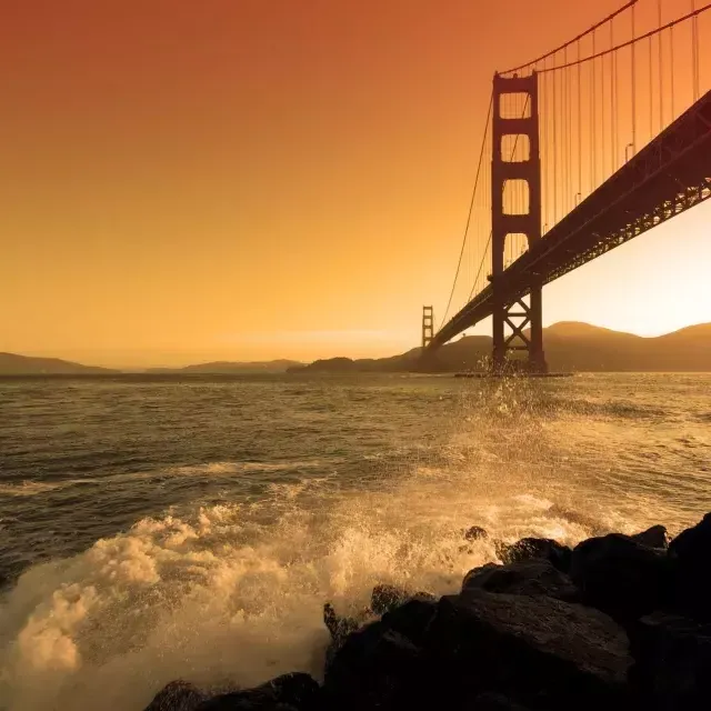 Les vagues s'écrasent près de Fort Point sous le Golden Gate Bridge au sunset .